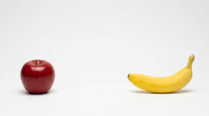 A shiny red apple and a ripe yellow banana on a white background.
