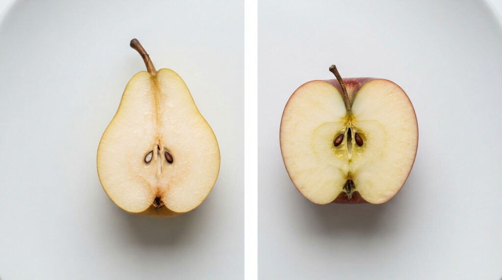 A halved pear and apple on a white plate, showcasing their seeds and textures.