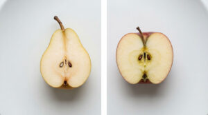 A halved pear and apple on a white plate, showcasing their seeds and textures.