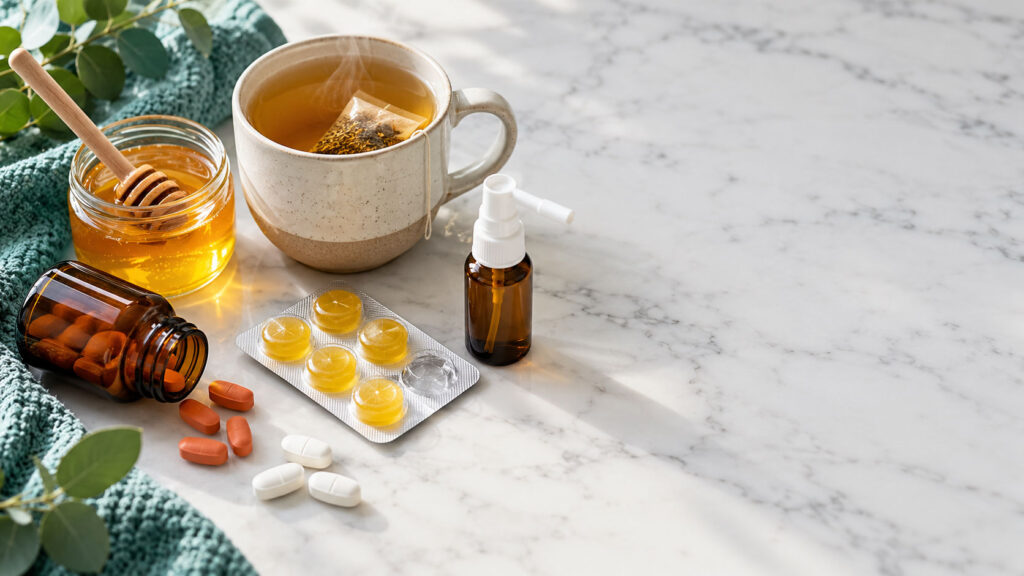 A cup of tea, honey jar, and various supplements on a marble surface.